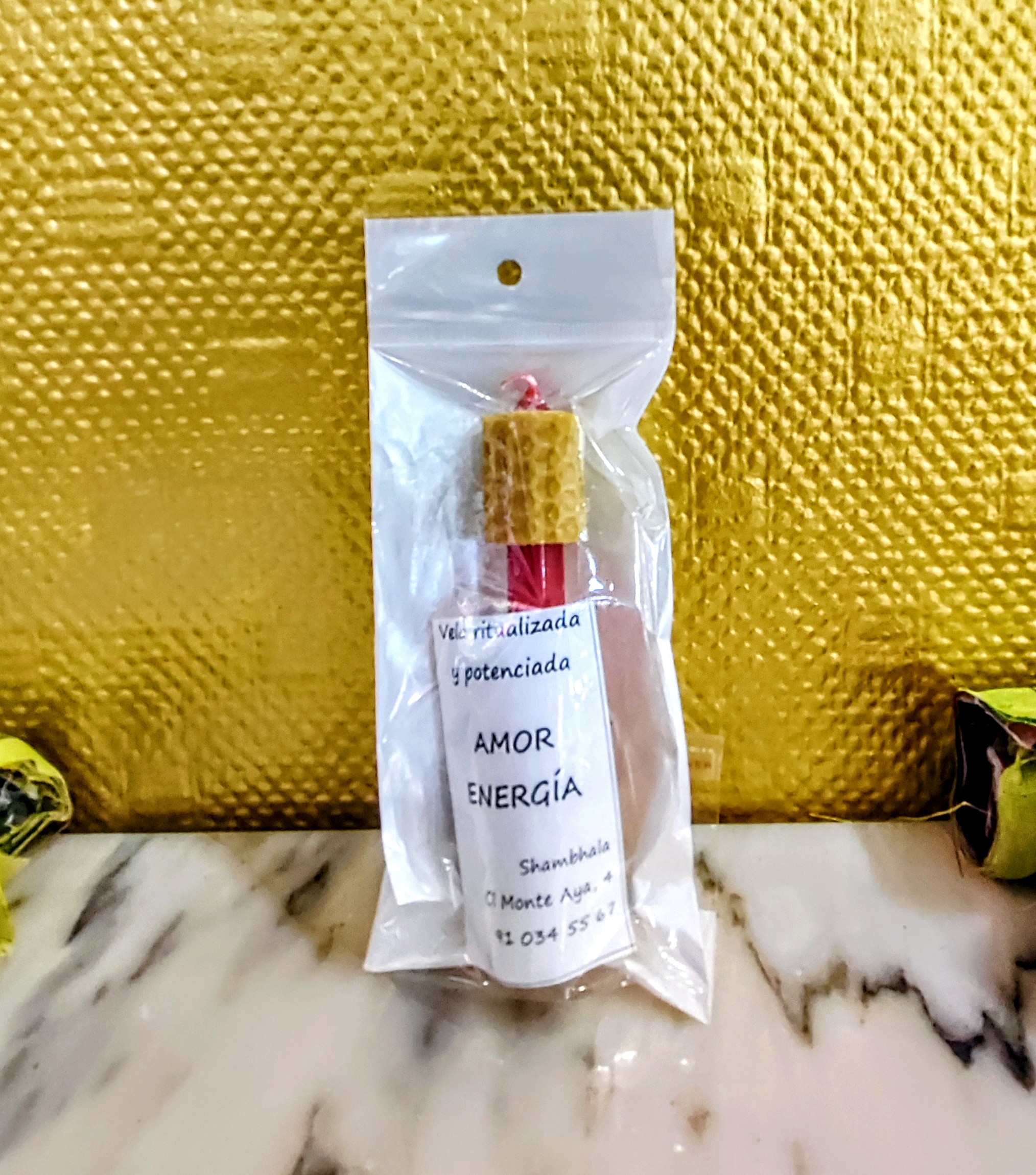 Pack de vela ritualizada artesanal de panal de abeja (textura de miel) color rojo, en su envoltorio original con etiqueta de AMOR y ENERGÍA de Shambhala.